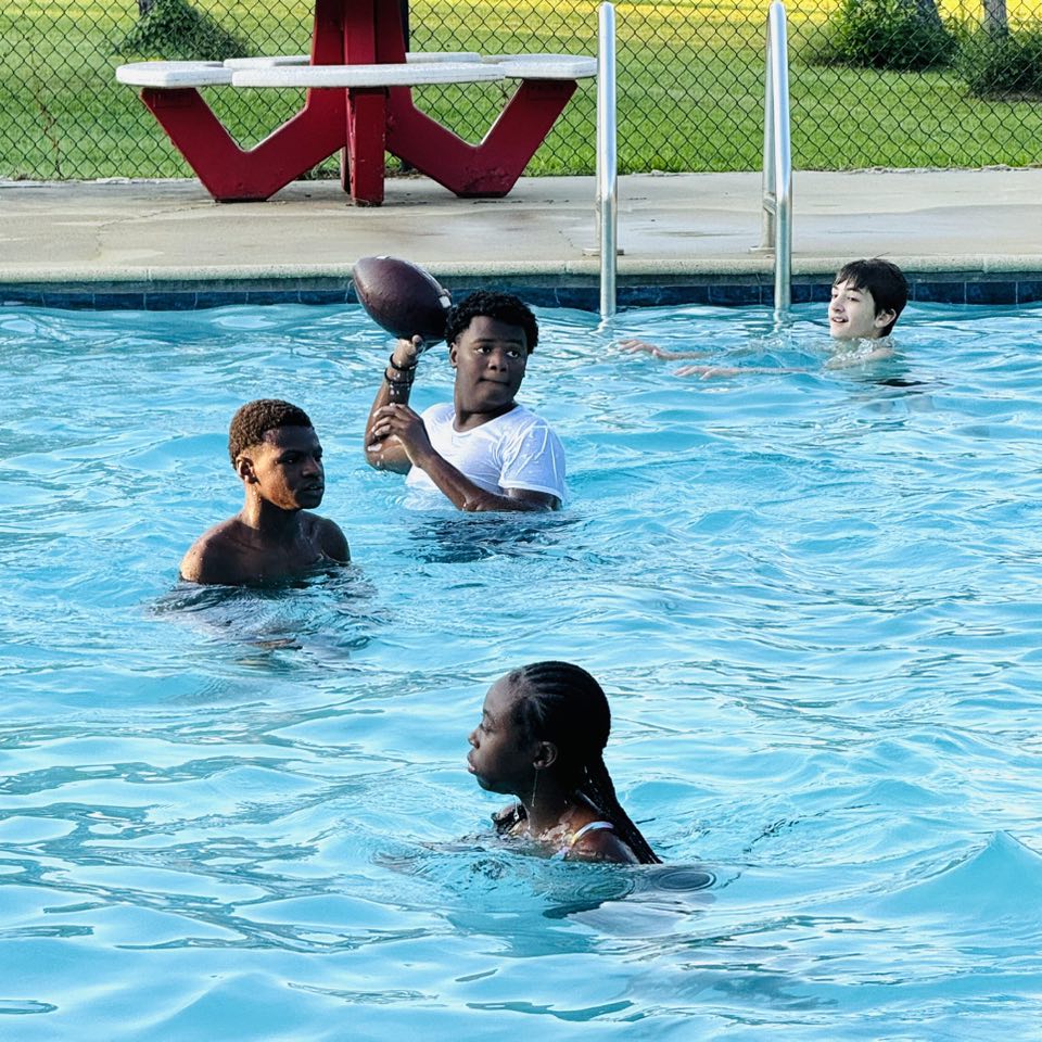 A boy in a pool about to throw a football.